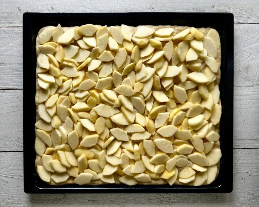 Teig mit Apfelfüllung belegt für Hefe-Apfelkuchen mit Streusel.