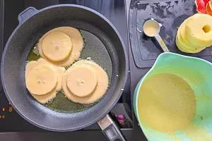 Teig und Apfelscheiben in der heißen Pfanne portionieren