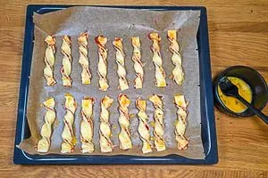 Teigstreifen wie eine Kordel zu Pizzastangen verdrehen und mit Ei bestreichen