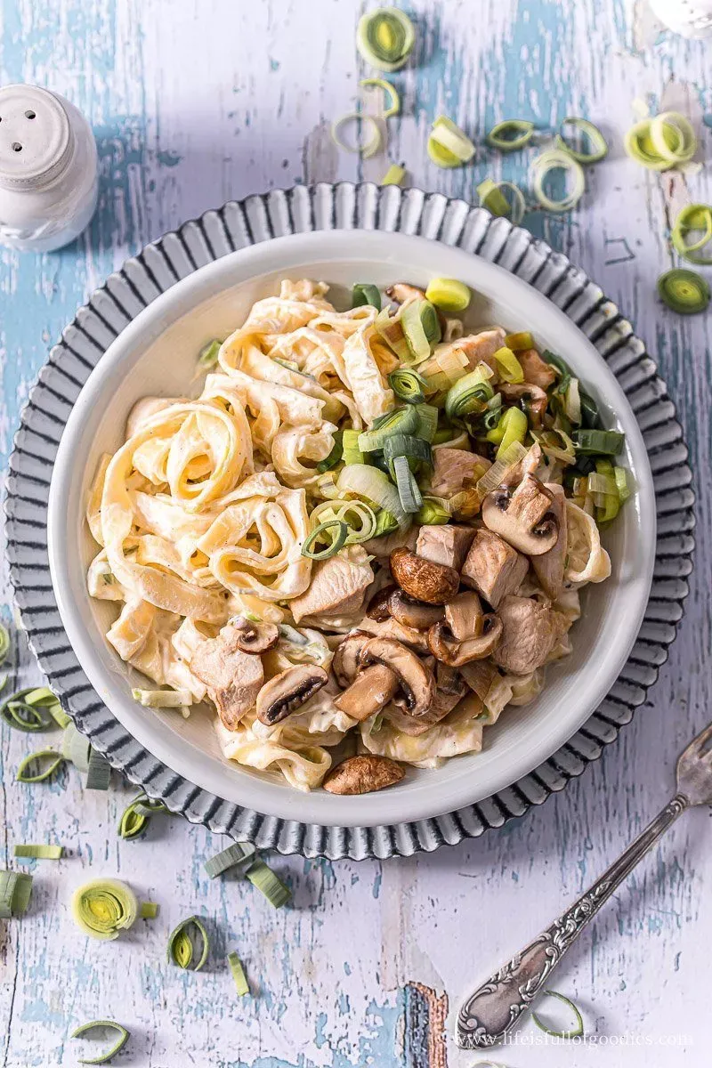Teller mit cremiger Frischkäsepasta, Putenbrust, Lauch und Champignons, fertig zum Servieren