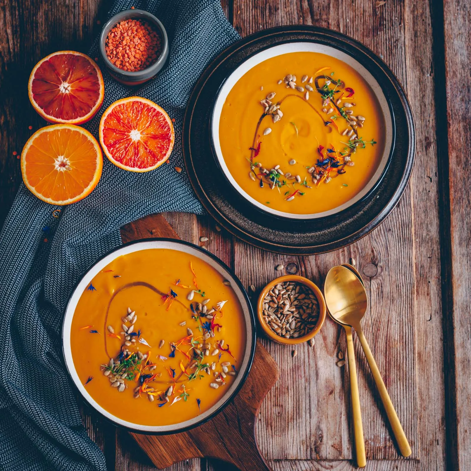 Teller mit cremiger Linsen-Orangen-Suppe, garniert mit Sonnenblumenkernen und frischer Kresse, ein perfektes Rezept mit Orangen.