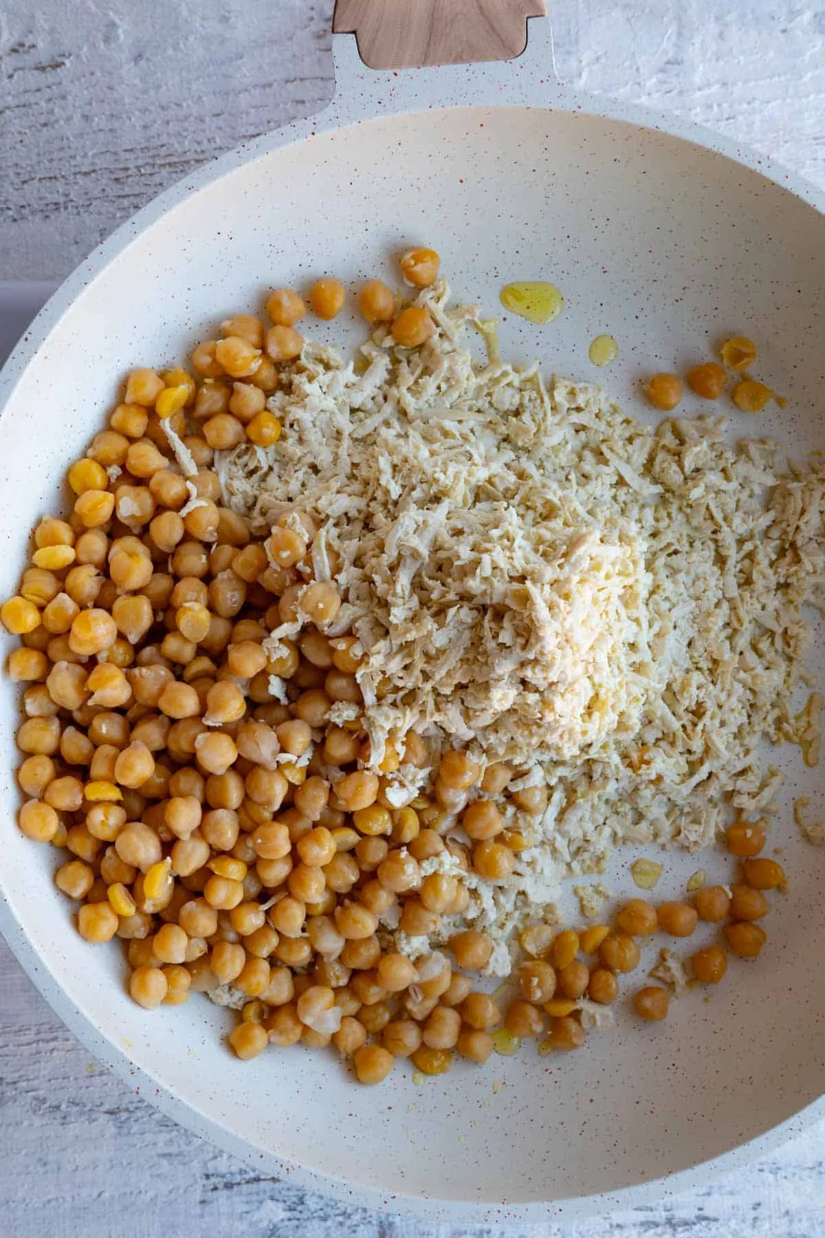 Tofu- und Kichererbsenmischung wird in einer weißen Pfanne angebraten.