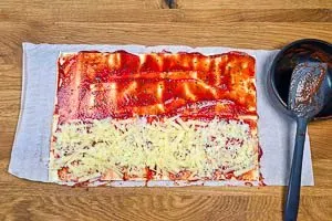 Tomatensoße auf den Teigbahnen verstreichen