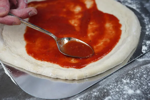 Tomatensoße gleichmäßig auf dem Pizzateig verteilen