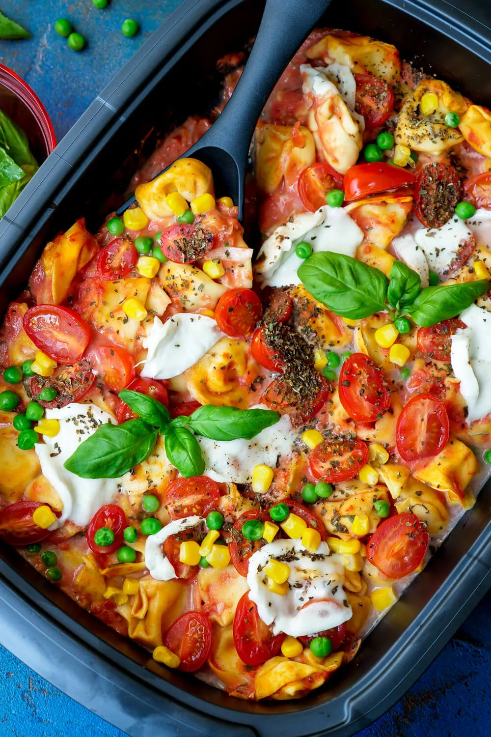 Tortelliniauflauf mit Tomatensauce, Mais, Erbsen, Tomaten und Mozzarella. Alternative Text: Herzhafter Tortelliniauflauf mit frischem Gemüse wie Mais, Erbsen und Tomaten, überbacken mit cremigem Mozzarella, ein ideales Gericht für ein gesundes Familienmittagessen.