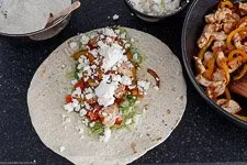 Tortilla reichlich befüllt mit allen Zutaten wie Hähnchen, Gemüse und Feta