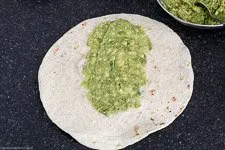 Tortilla wird mit Avocadocreme bestrichen, vorbereitet zum Befüllen