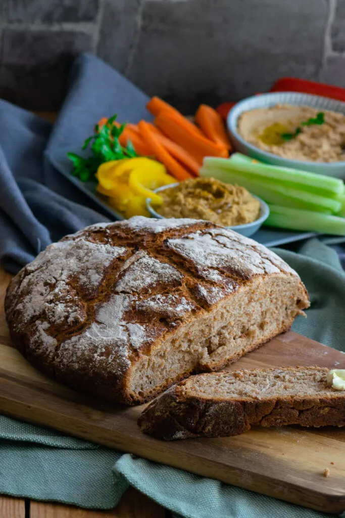 Traditionelle deutsche Brotzeit mit selbstgebackenem Bauernbrot, Hummus und frischer Rohkost