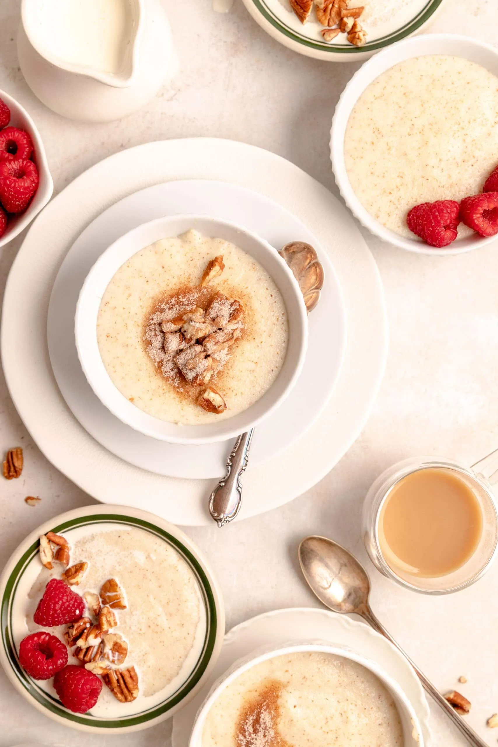Traditioneller Grießbrei mit frischen Beeren, Zimt-Zucker und Nüssen serviert in Schüsseln auf einem Holztisch, perfekt für ein deutsches Frühstück.