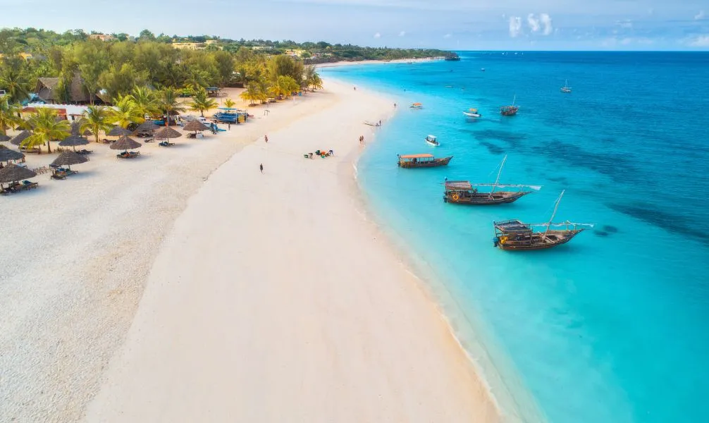 Traumstrand auf Sansibar mit traditionellem Boot im klaren Indischen Ozean, ein ideales Ziel für einen warmen Weihnachtsurlaub
