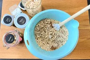 Trockene Zutaten für Granola: Haferflocken, gehackte Nüsse, Leinsamen, Sesam, Zimt und Salz in einer Rührschüssel vermengen.