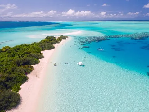 Türkises Wasser an einer Landzunge auf den Malediven mit zwei Booten und Menschen