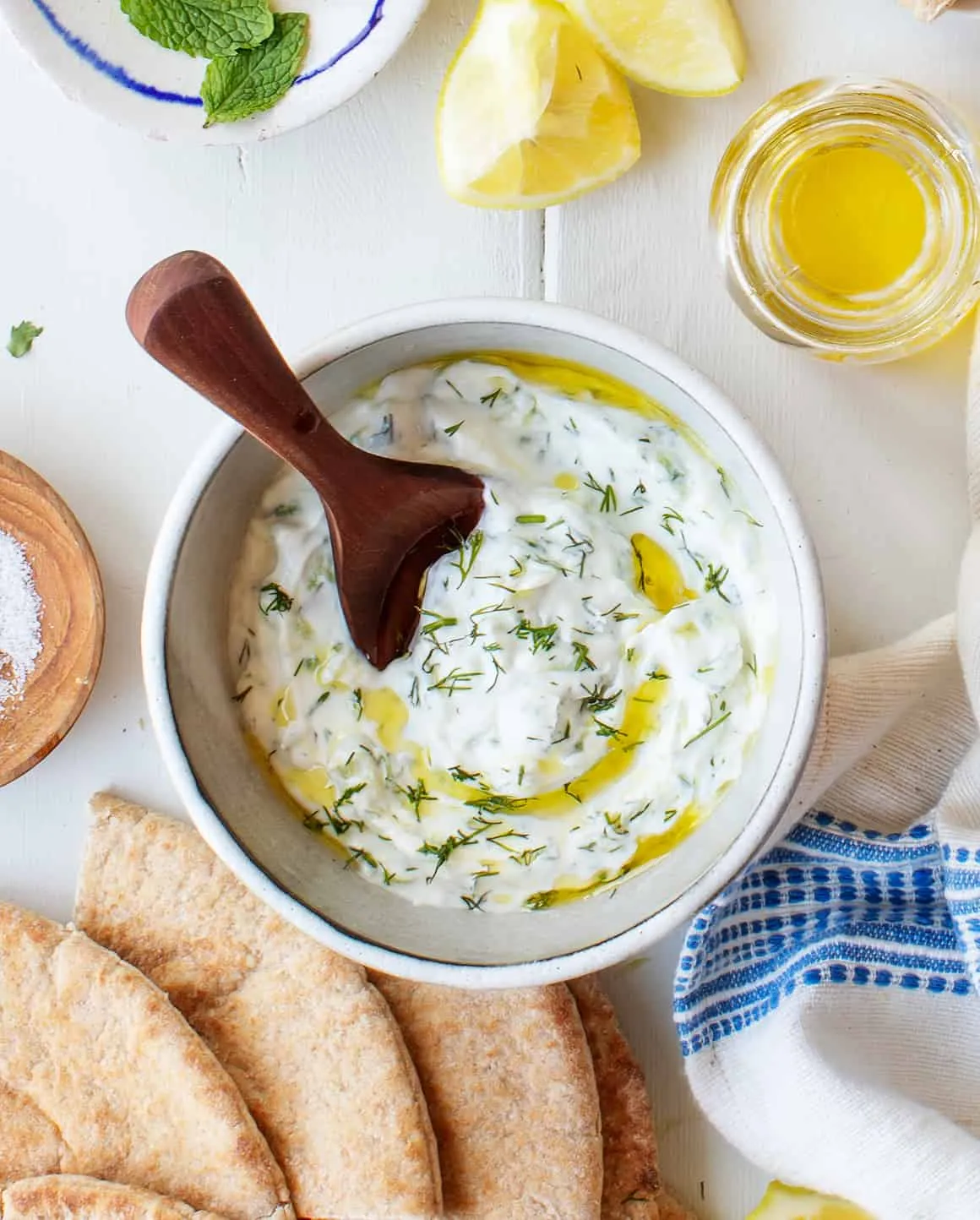 Tzatziki mit Gurkenscheiben, Olivenöl und frischen Kräutern in einer Servierschale, ideal als Beilage für einen sommerlichen Grillabend.