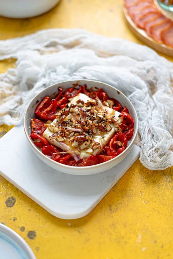 Überbackener Ziegenkäse mit Mandelkruste und karamellisierten Zwiebeln auf einem Tomatenbett