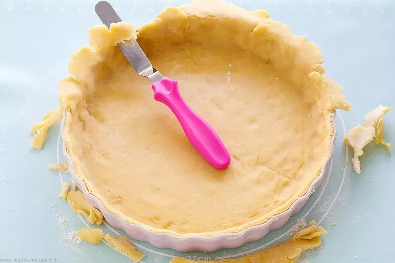 Überstehenden Quiche Teig mit Messer oder Palette sauber abschneiden.