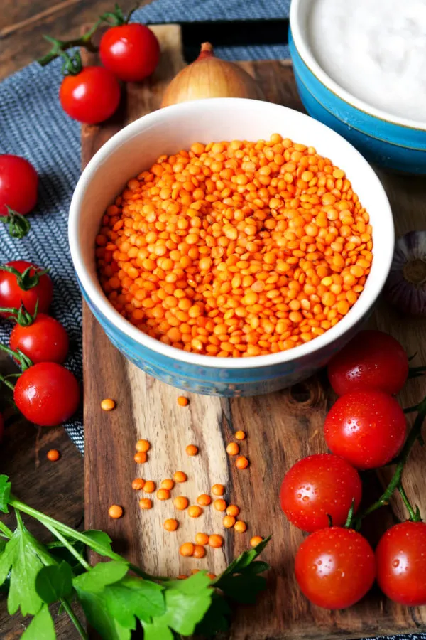 Ungekochte rote Linsen in einer Holzschale, bereit zum Spülen und Kochen
