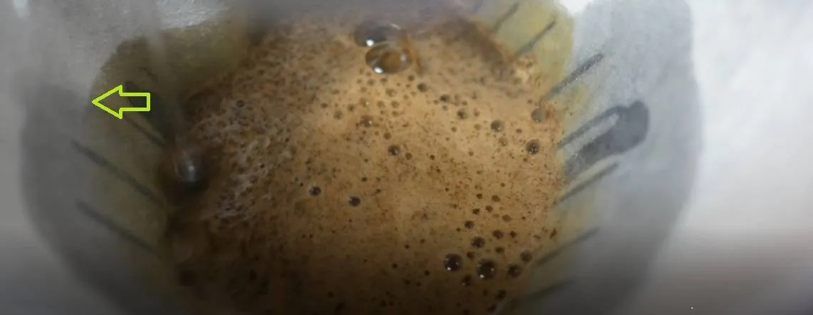 Unscharfes Bild, das zeigt, wie ein Wasserstrahl den Papierfilter anstelle des Kaffeemehls benetzt