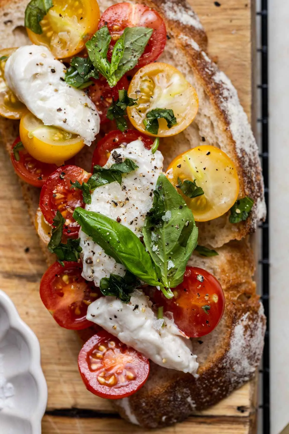 Vegane Burrata, serviert auf geröstetem Sauerteigbrot mit frischen Tomaten und Basilikum