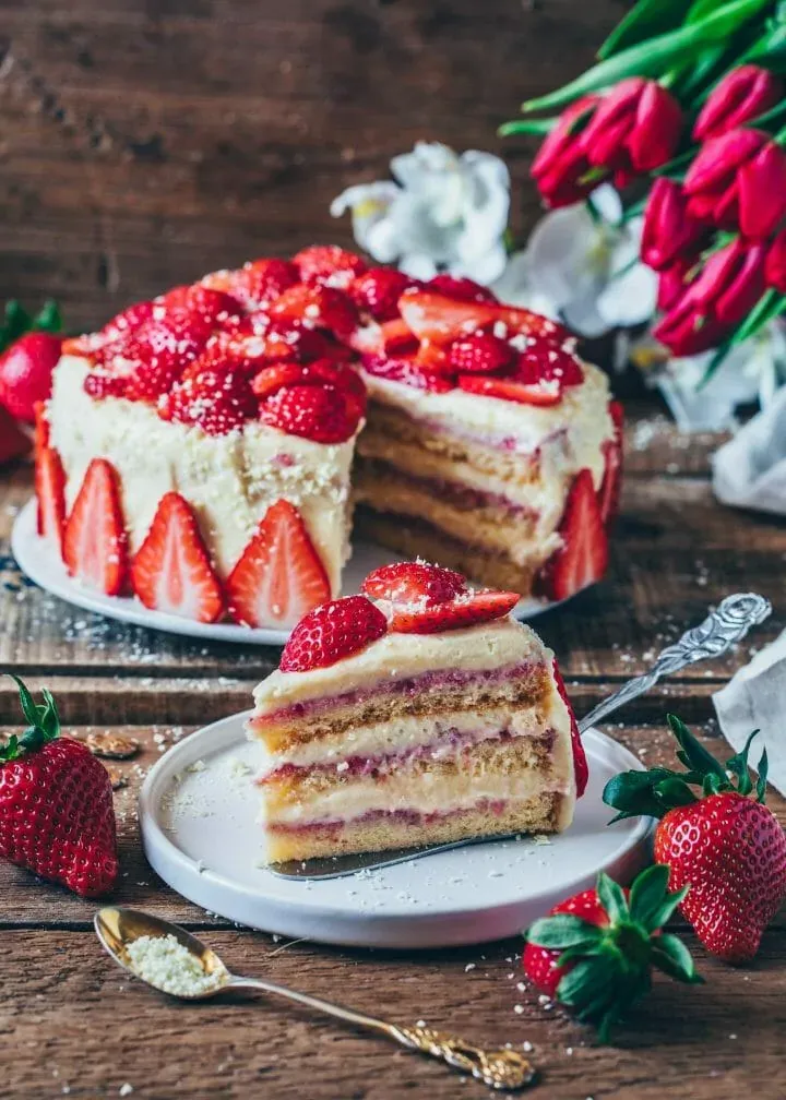 Vegane Erdbeer Sahne Torte mit weißer Schokolade dekoriert, ideal für sommerliche Kaffeetafel