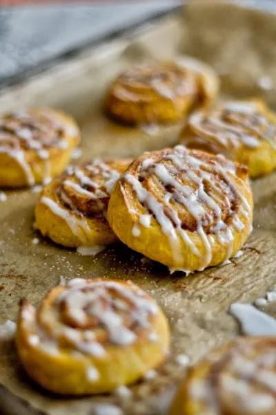 Vegane Kürbis-Zimtschnecken auf Backpapier, frisch aus dem Ofen