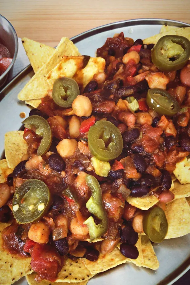 Vegane Nachos mit Chili-Topping und einer Beerensauce, präsentiert auf einem Teller