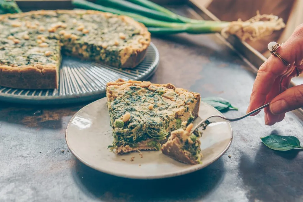 Vegane und glutenfreie Spinat Quiche vor idyllischer Kulisse