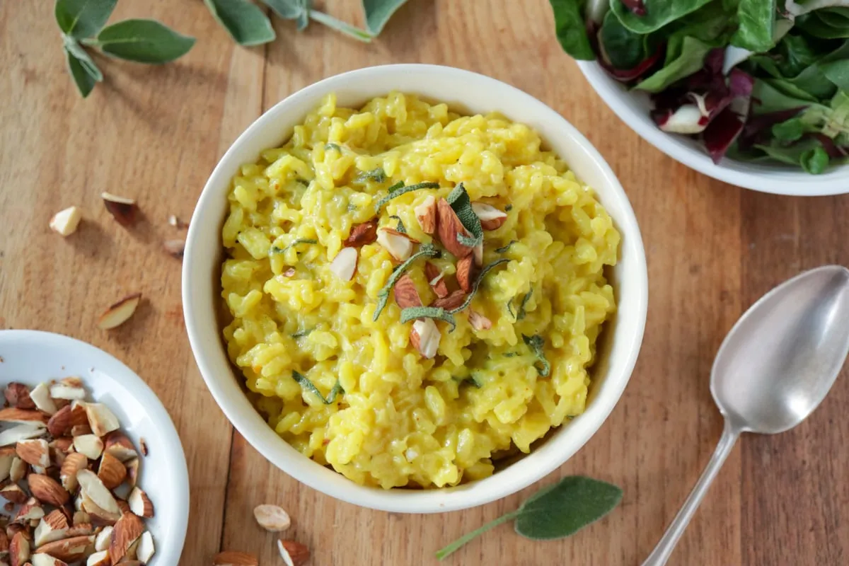 Veganes Safranrisotto mit frischem Salbei und Mandeln in einer Schüssel, bereit zum Servieren.