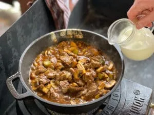 Verfeinerung des Boeuf Stroganoff mit cremiger Sahne am Ende der Zubereitung