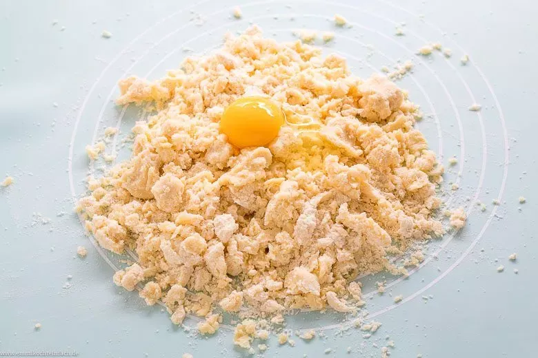 Verkneten des Quiche Teigs mit Ei und Handballen bis zur Geschmeidigkeit.