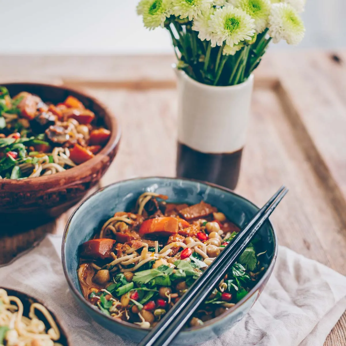 Verschiedene Zutaten für die Zubereitung eines Kürbis-Currys, darunter Kürbis, Kichererbsen, Kokosmilch und Mie-Nudeln.