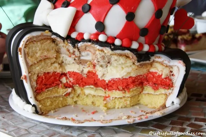 Verzierungen aus Fondant in Form von Spielkartensymbolen und Alice im Wunderland Elementen auf der Torte.