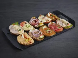 Vielfältige Brötchen auf Schwarzbrot mit Hummus, Braten und Käse