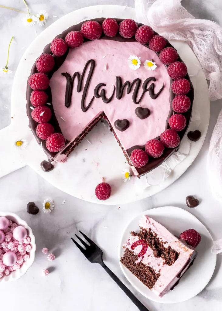 Von oben fotografierte Himbeermousse-Torte mit Schokodrip und &quot;Mama&quot; Schriftzug.
