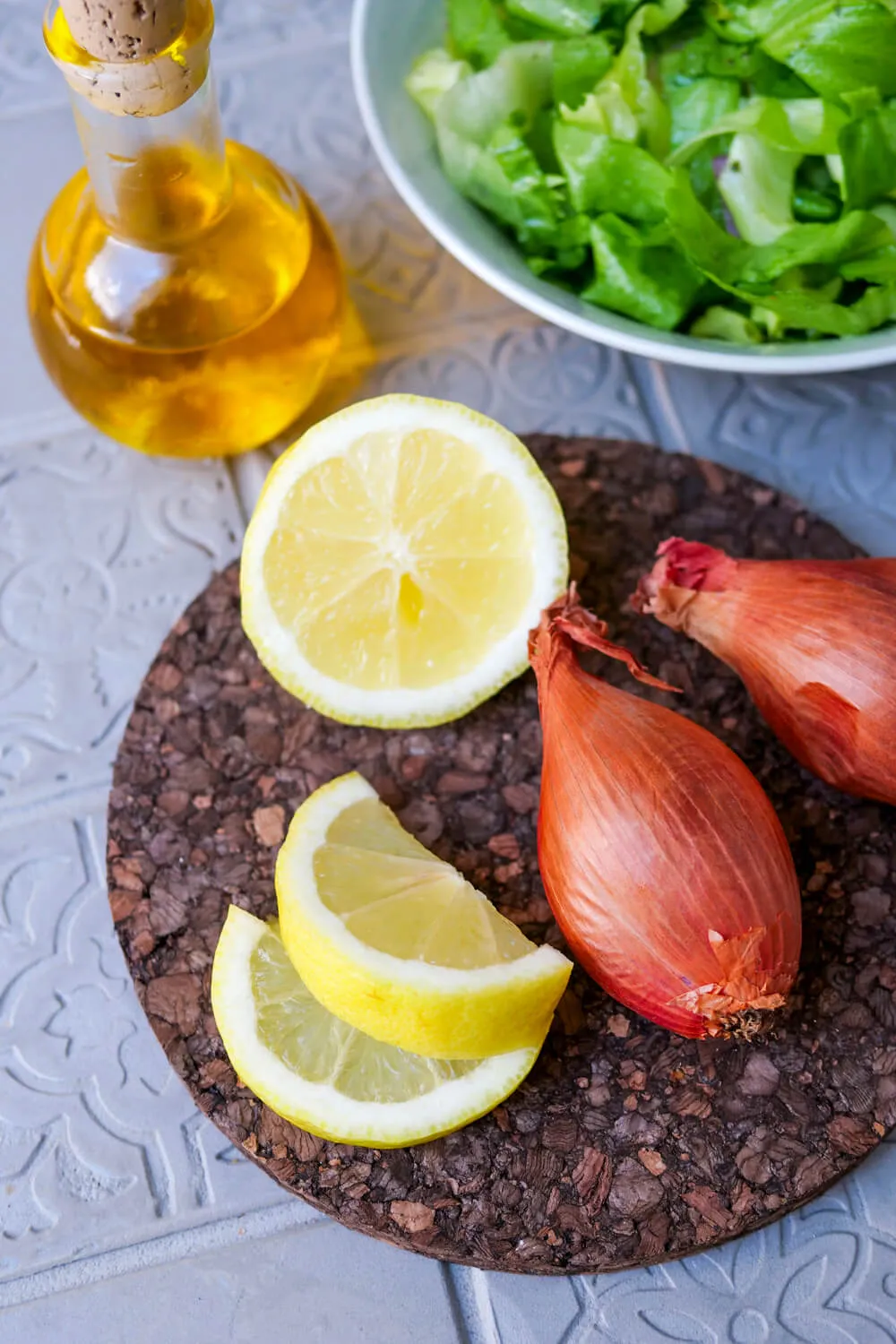 Vorbereitete Zutaten für das Endiviensalat-Dressing: Endiviensalatblätter, frische Zitrone, Schalotten und eine Schale Olivenöl.
