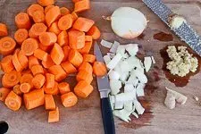 Vorbereitungsschritt: Geschälte Karotten und Zwiebeln geschnitten auf einem Schneidebrett