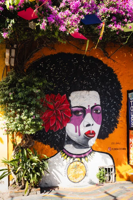 Wandgemälde einer Frau mit Afro-Frisur, Blume im Haar und lila umrandeten Augen
