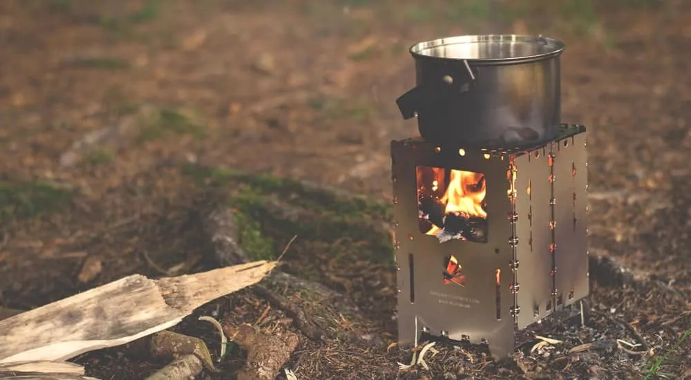 Wasser kochen auf einem Campingkocher in der Natur, vorbereitend für die Outdoor-Kaffeezubereitung mit einer Reise Kaffeemaschine.
