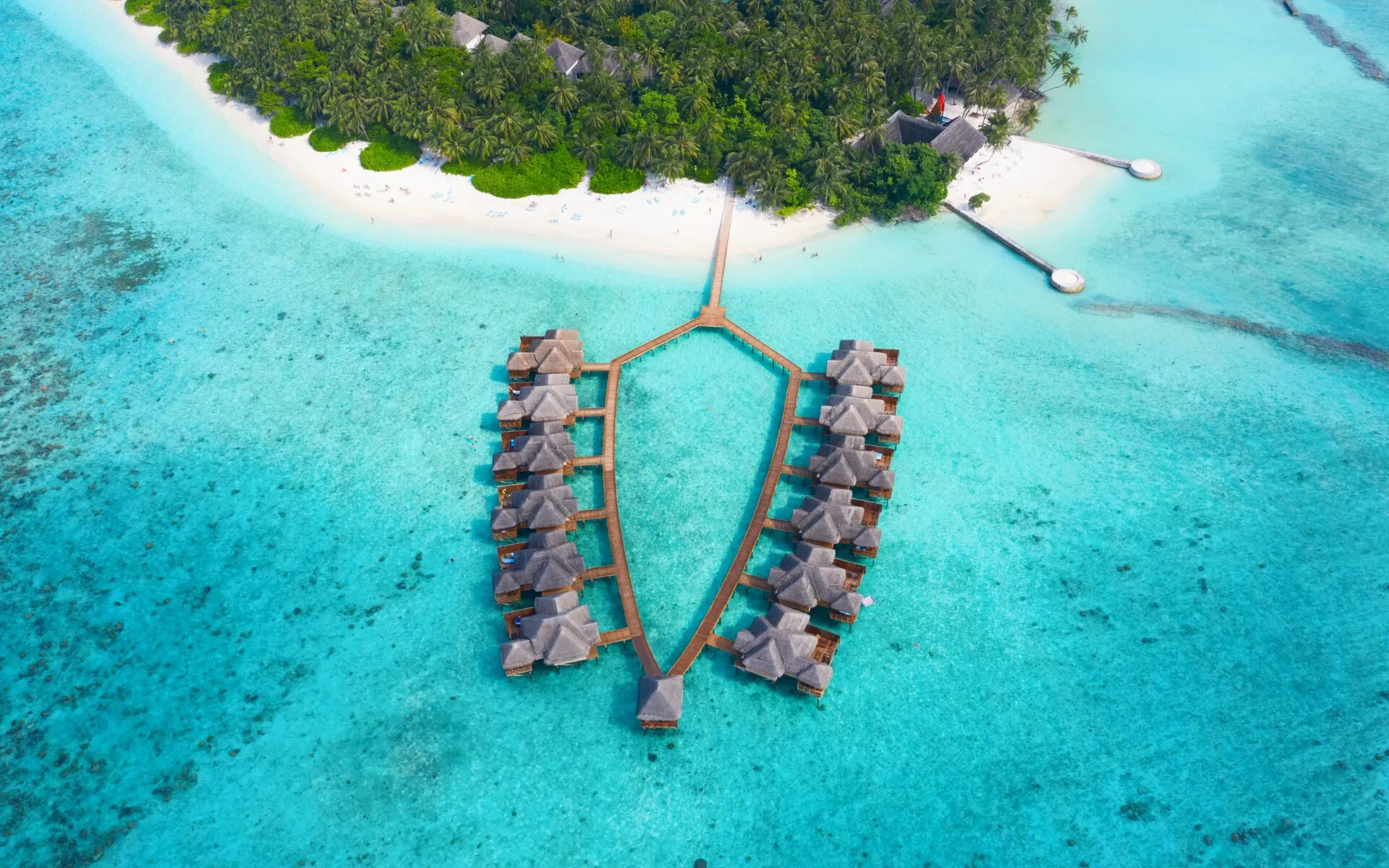 Wasserbungalows und ein Steg auf den Malediven bei Sonnenuntergang