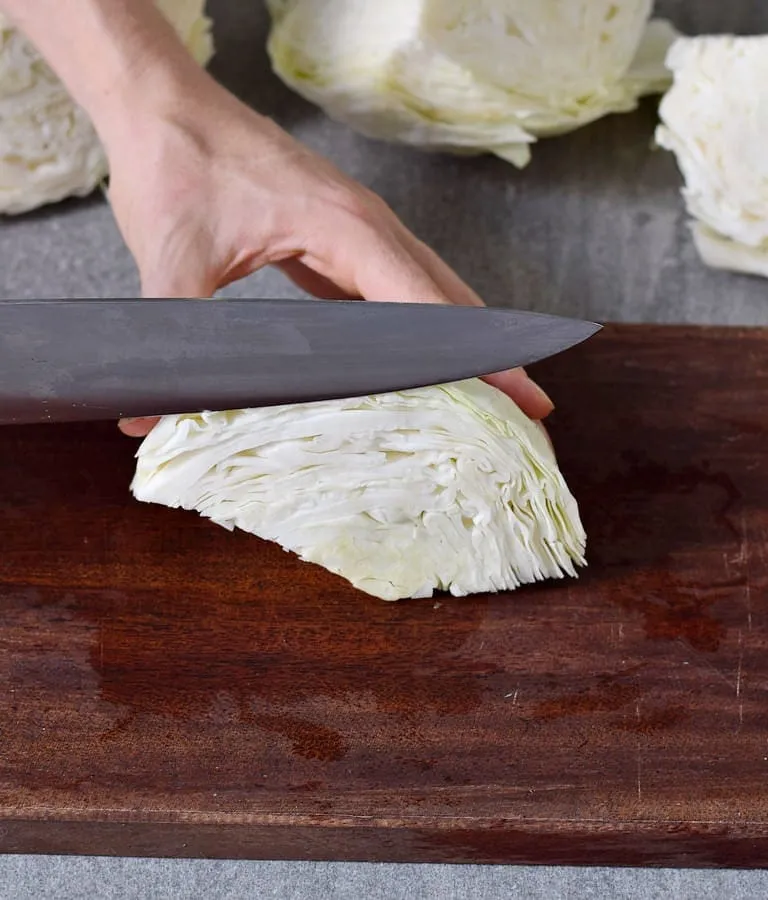 Weißkohl mit einem großen Messer auf einem Holzbrett schneiden