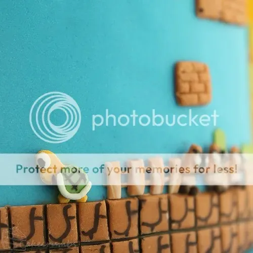 Winzige Super Mario Gegner aus Fondant, darunter Goombas und Koopa Troopas, liebevoll als Dekoration auf dem Geburtstagskuchen platziert.