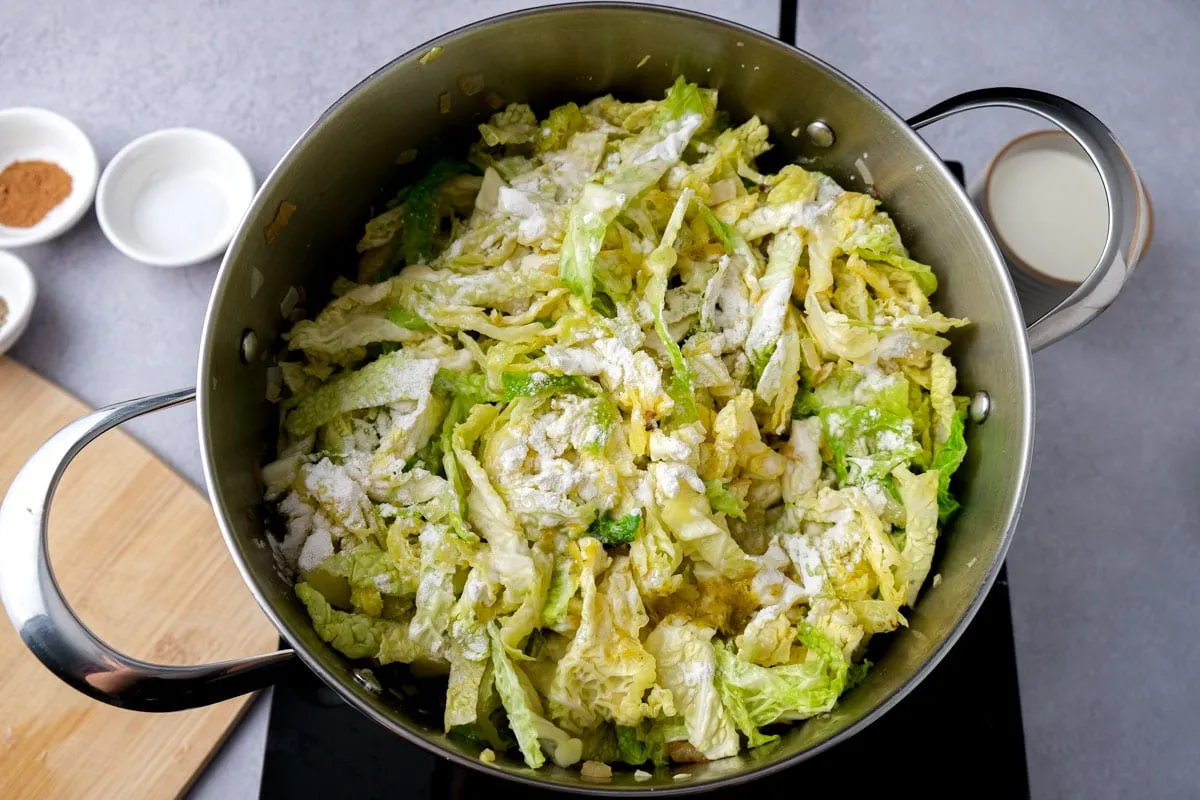Wirsingkohl im Topf wird mit Mehl bestreut, um die Sauce für den Rahmwirsing zu binden.