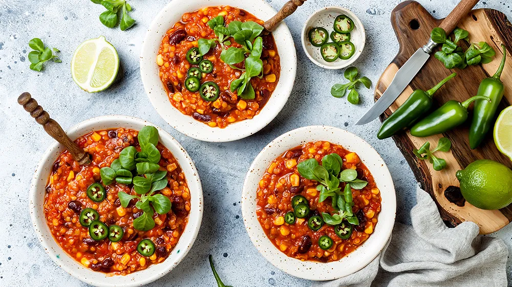 Würziger Chili sin Carne mit roten Linsen, Mais und Bohnen, garniert mit Koriander