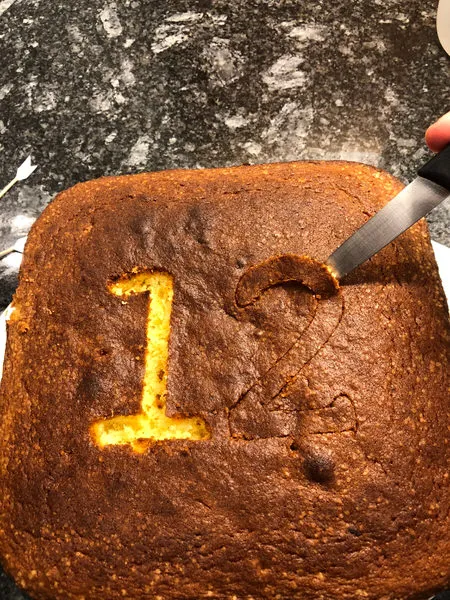 Zahlenform im Kuchen: Die ausgeschnittenen Zahlenbereiche auf dem Blechkuchen, bereit für die Glasur und Dekoration.