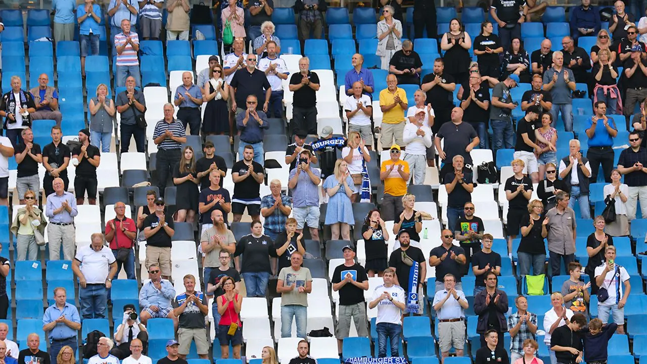 Zahlreiche Menschen erheben sich und spenden Applaus, um Abschied von Uwe Seeler zu nehmen