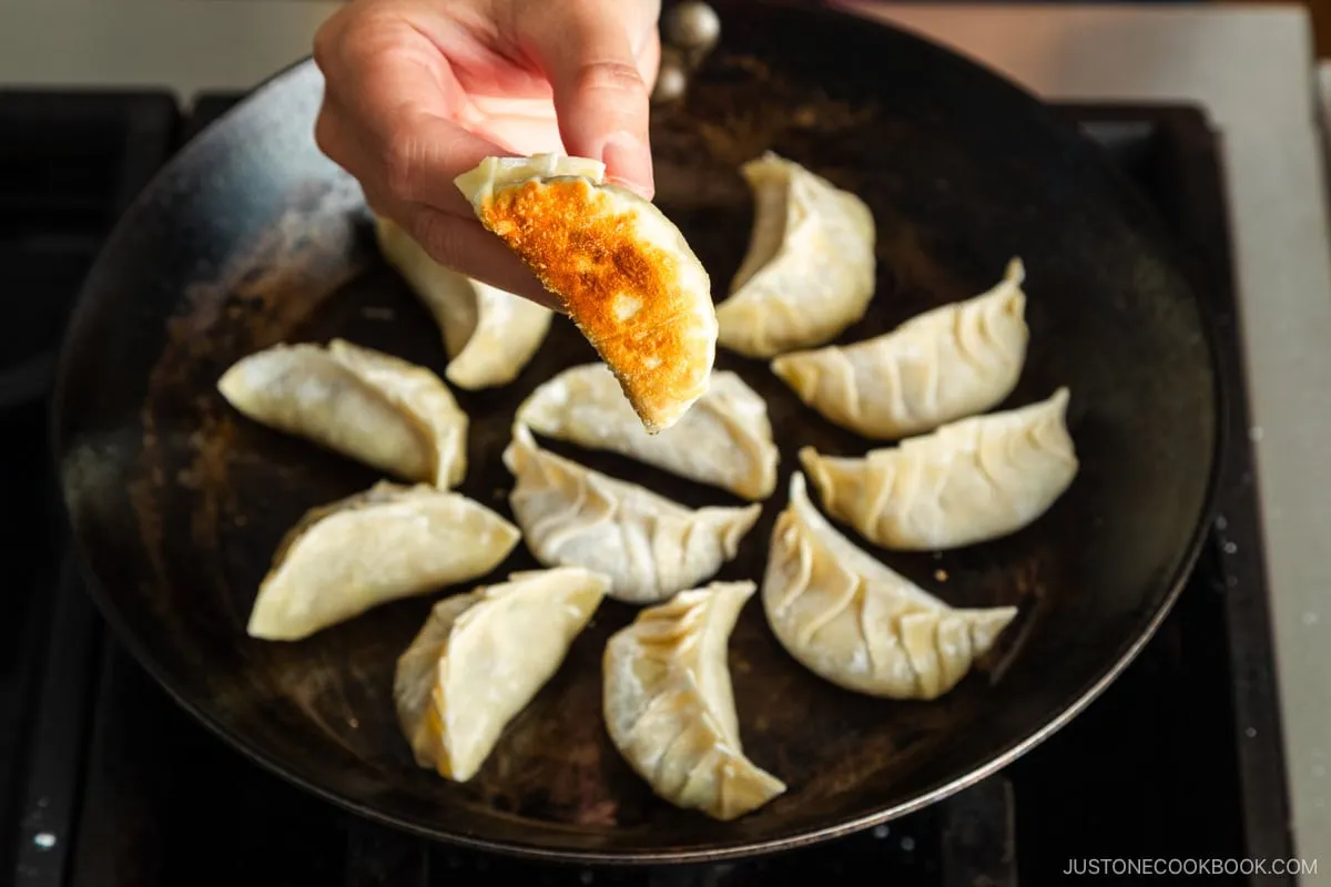 Zeigen der angebratenen Gyoza-Unterseite.