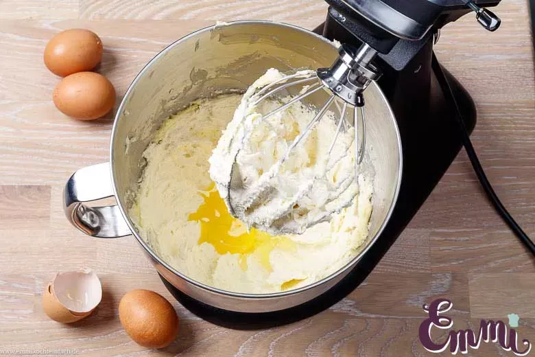 Zimmerwarme Eier, die einzeln in eine helle, cremige Butter-Zucker-Mischung für den Marmorkuchen-Teig gerührt werden