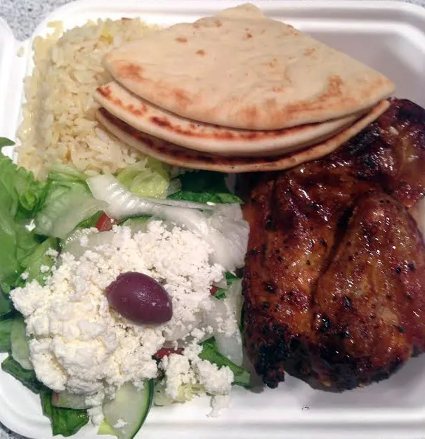 Zitronenhähnchen-Teller des Santorini Grill mit griechischem Salat, Reis und Pitabrot. Ein klassisches Gericht der griechischen Küche.