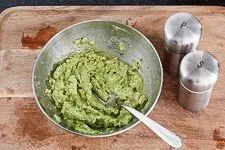 Zubereitung der Avocadocreme in einer Schüssel mit Gabel und Gewürzen