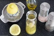 Zubereitung des Dressings für griechischen Salat mit Olivenöl und Zitronensaft in einem Glas.