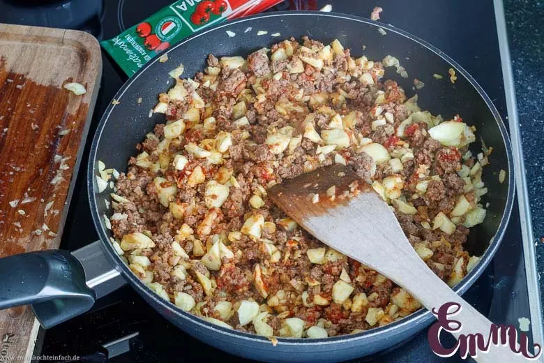 Zucchinifruchtfleisch und Tomatenmark werden in der Pfanne mit dem Hackfleisch vermengt